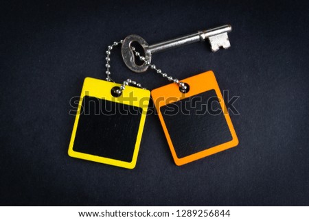 Key and wooden tag on black background with selective focus and crop fragment. Business and copy space concept