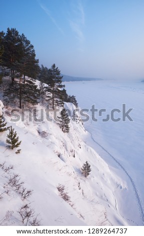 Steep slope of river Tom under the snow and ice in winter season. 
