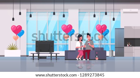 couple drinking wine man woman lovers watching tv on couch modern apartment home interior air heart shape balloons happy valentines day concept flat horizontal
