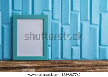 Blue photo frame on old wooden table over blue wallpaper background