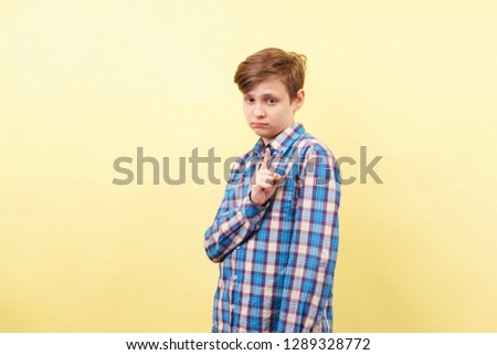 warning, admonition or notice. boy making forewarning gesture over yellow background, advertisement, banner or poster template, emotion facial expression, people reaction