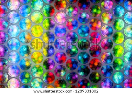 An abstract multicolored background created with a colorful image through a sheet of plastic bubble wrap protective packaging