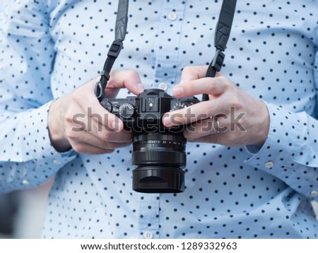 young man 's hands holding a digital camera to take photos of something,  the activity of camera man's hobby lifestyle in city, using camera technology concept