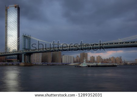 View of the Manhattan Bridge and Manhattan from the riverside of the East River at sunset 