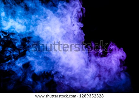 Clubs of colored smoke of blue and pink color on a black isolated background in the form of soft clouds from the vape