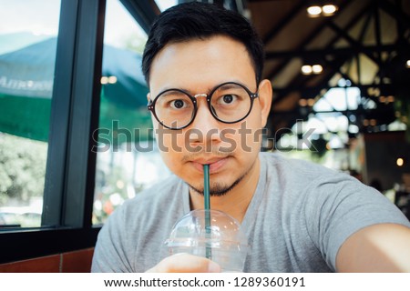 Asian man with glasses selfy himself drink coffee in the cafe.
