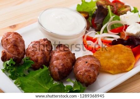 Tasty  balkan minced meat kebapcheta served with onion,  tomatoes, lettuce and sauce