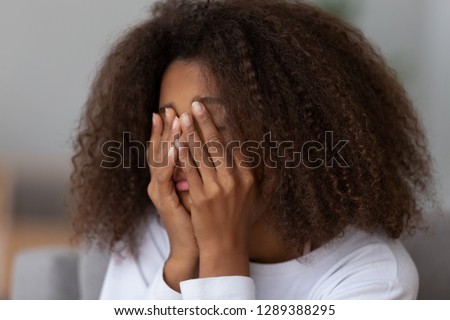 Close up of upset African American teenage girl cover face with hands, feel disappointed having problems at school, sad black teen outsider cry at home, suffering from discrimination Royalty-Free Stock Photo #1289388295
