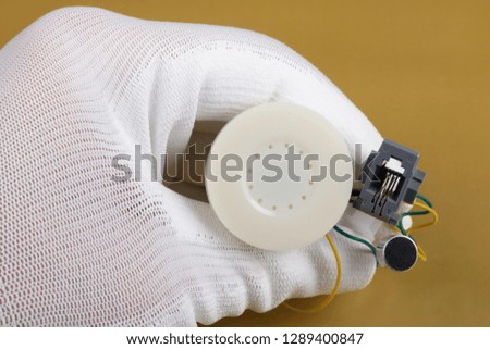 A technician controls the quality of a mini speaker an microphone  for phone handset. Mass production. Modern technology  macro concept.