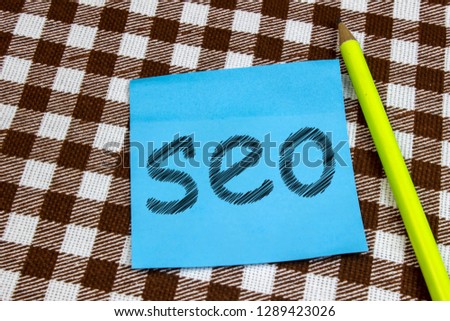 The blue sheet with the word SEO lies on the checkered fabric with a pencil