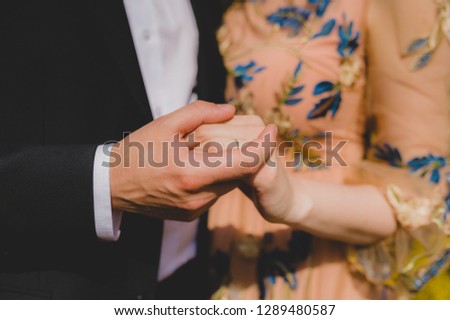 Bridal couple holding hands. Close-up picture without faces.