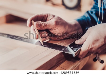 Woodwork and furniture making concept. Carpenter in the workshop marks out the details of the furniture cabinet using a setsquare close up view Royalty-Free Stock Photo #1289531689