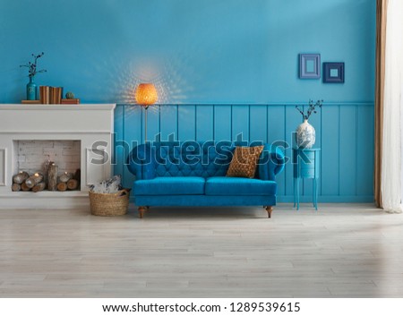 Blue room decoration, blue sofa and wall concept, white fireplace with wood, frame and middle table and carpet decoration. Lamp and frame style.