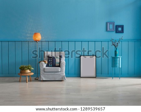 Blue wall and background room, decorative sofa and middle table, armchair and pillow detail, lamp and frame decoration with carpet decor.