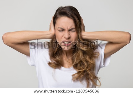 Annoyed stressed woman cover ears feel hurt ear ache pain otitis suffer from loud noise sound headache, irritated stubborn girl deaf hear not listen to noisy music isolated on white studio background Royalty-Free Stock Photo #1289545036