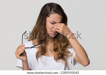 Tired teen girl taking off glasses rubbing eyes isolated on white blank studio wall background, young fatigued woman feeling dry irritable eye strain, bad blurry vision problem tension concept Royalty-Free Stock Photo #1289545042