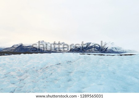 close view on glacial ice with snow civered mountain in background