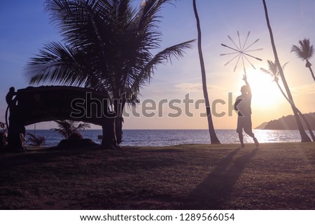 Man spinning contact staff or stick on the beach with sunrise background in the morning.