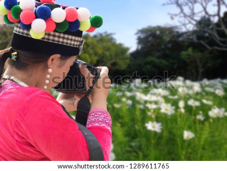 Pretty girl using a digital camera to taking pictures of flowers.