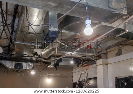 Installation and repair of frame, ventilation system, fire alarm, electric cable, lamp bulb before assembling stretch or suspended ceiling. Concept of reconstruction in an office building