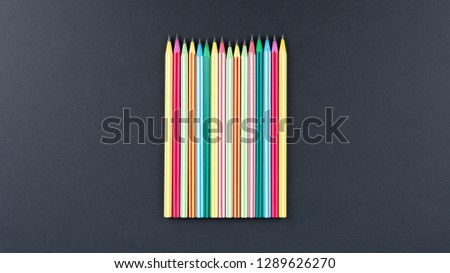 colored pencils in row on black background top view. Art set of pencils for schoolboy with free space. view from above