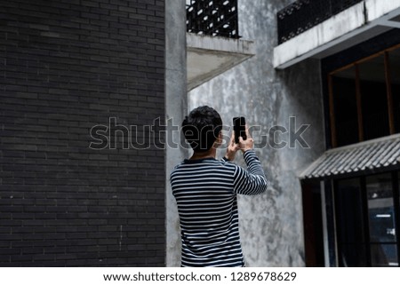 Middle age tourist taking mobile photo of skyscrapers using his smart phone with blank screen