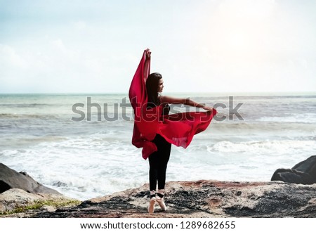 The abstract art design background of beauty lady wearing red suit and satin ballet shoes,point leg and raise hands up in the air,posing ballet pattern,on the beach