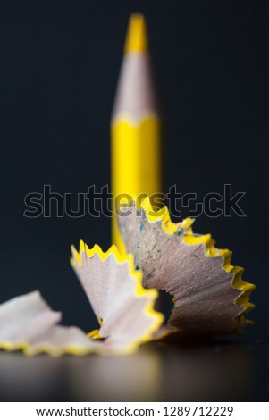 Yellow pencil and shavings on black background. Selective focus.