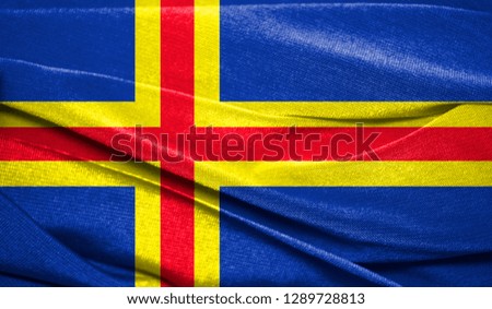 Realistic flag of Aland on the wavy surface of fabric. Perfect for background or texture purposes