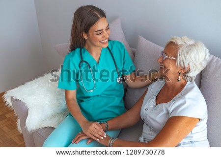 Young caring lovely caregiver and happy ward. Image of caregiver and senior resting in the living room. Smiling caregiver taking care of a happy elderly woman Royalty-Free Stock Photo #1289730778