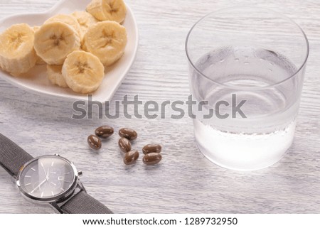 Sliced and whole bananas. On a white plate. On the old wooden table. Misted with clean water. The concept of a healthy diet and diet.