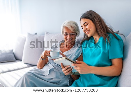 Happy patient is holding caregiver for a hand while spending time together. Professional helpful caregiver comforting smiling senior woman at nursing home Royalty-Free Stock Photo #1289733283