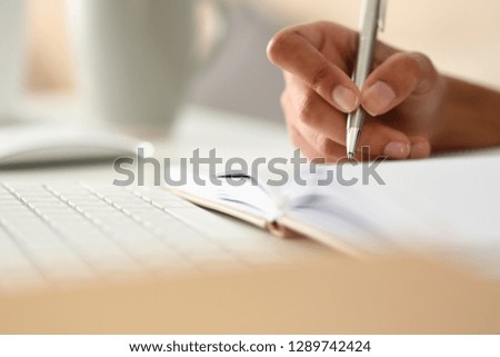 Female hand holding silver pen ready to make note in opened notebook sheet. Businesswoman sign at workspace make thoughts records at personal organizer white collar conference signature concept