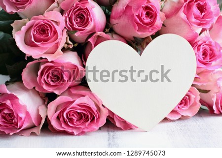 Beautiful retro soft pink rose flower background with wooden heart and room for text.