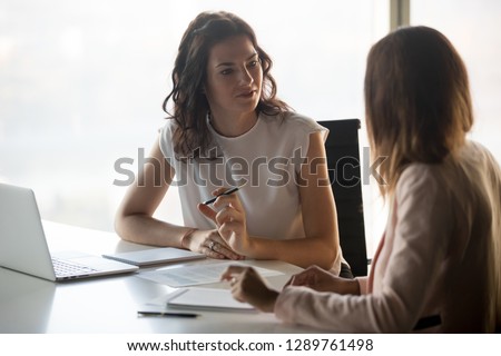 Two diverse serious businesswomen discussing business project working together in office, serious female advisor and client talking at meeting, focused executive colleagues brainstorm sharing ideas Royalty-Free Stock Photo #1289761498