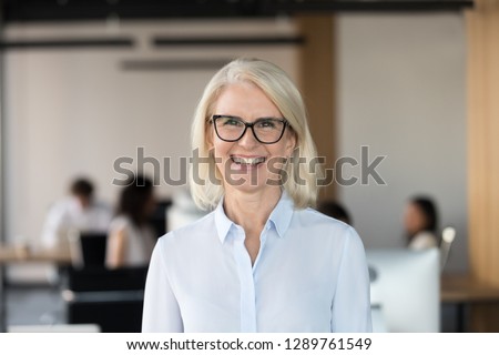 Cheerful senior businesswoman in glasses looking at camera, happy older team leader ceo manager, female aged teacher professor or mature executive woman mentor smiling in office head shot portrait Royalty-Free Stock Photo #1289761549