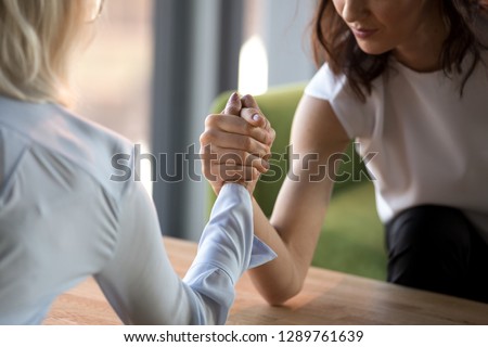 Young and old businesswomen compete arm wrestling fighting for leadership feeling jealous envious about other success, female rivals armwrestling struggling, generations rivalry concept close up view