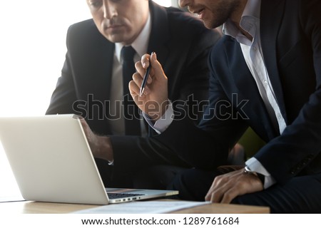 Serious businessmen in suits talk work together with laptop, financial advisor consulting convincing client about online investment benefits concept, make business offer with computer, close up view Royalty-Free Stock Photo #1289761684