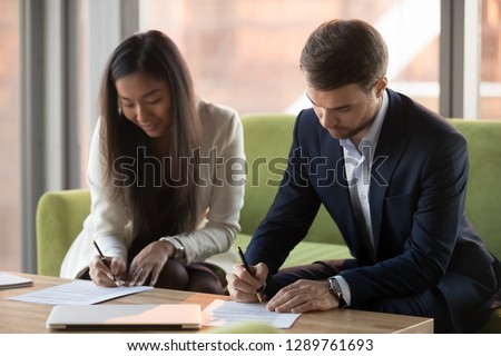 Asian businesswoman and caucasian businessman sign contracts documents at meeting, diverse male female business partners client and service provider put signature on legal papers making agreement Royalty-Free Stock Photo #1289761693