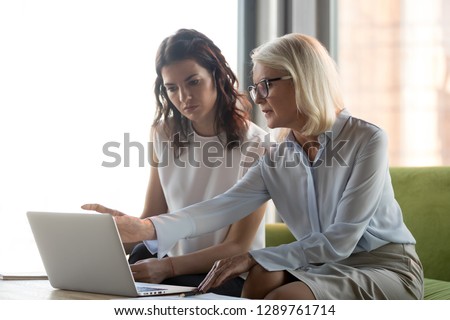 Serious middle aged executive manager explaining colleague online work together pointing at laptop, mature older financial advisor insurer or bank worker making offer to client, advisory services Royalty-Free Stock Photo #1289761714