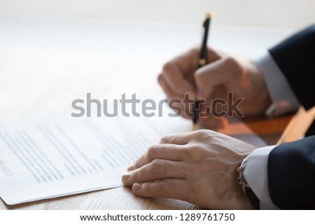 Close up view of male hand signing commercial financial contract concept, businessman put written signature on legal paper filling document form buy insurance, bank services, authorized registration Royalty-Free Stock Photo #1289761750