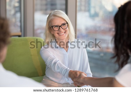 Smiling confident old mature woman job seeker applicant handshaking hr making good first impression at interview meeting, happy satisfied middle aged businesswoman shaking hand getting hired concept Royalty-Free Stock Photo #1289761768