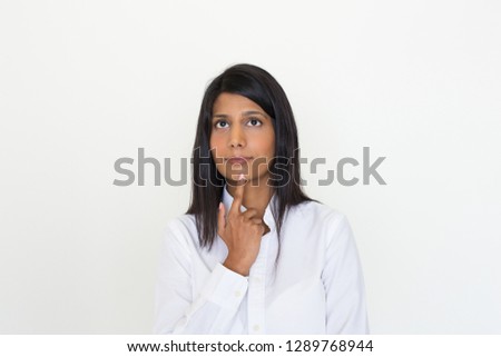 Pensive girl making decision. Young Indian woman wearing white office blouse, touching chin with finger an staring into vacancy. Thinking concept