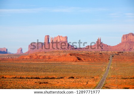Monument Valley is the long straight road (US 163), leading across flat desert towards sandstone buttes and pinnacles rock. Monument Valley Tribal Park, Nabajo Nation, Arizona/Utah, USA.