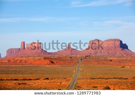 Monument Valley is the long straight road (US 163), leading across flat desert towards sandstone buttes and pinnacles rock. Monument Valley Tribal Park, Nabajo Nation, Arizona/Utah, USA.