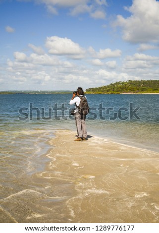 Tourist taking pictures at the tip of Coroa do Aviao islet, Itamaraca island on the right - Pernambuco, Brazil