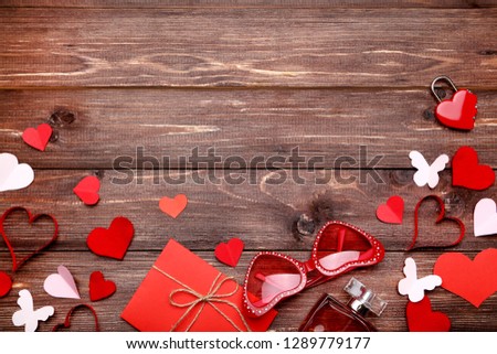 Paper hearts with envelope, sunglasses and perfume bottle on brown wooden table