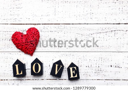 Red heart with word Love on white wooden table