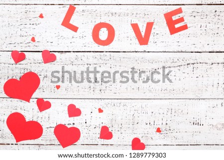 Red paper hearts with word Love on white wooden table