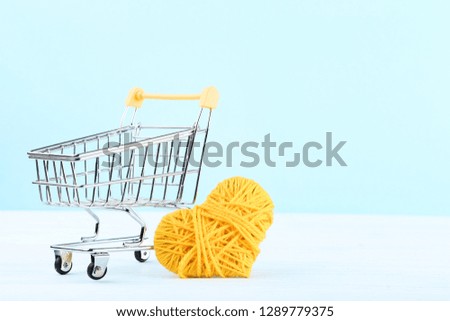 Shopping cart with yellow rope heart on wooden table
